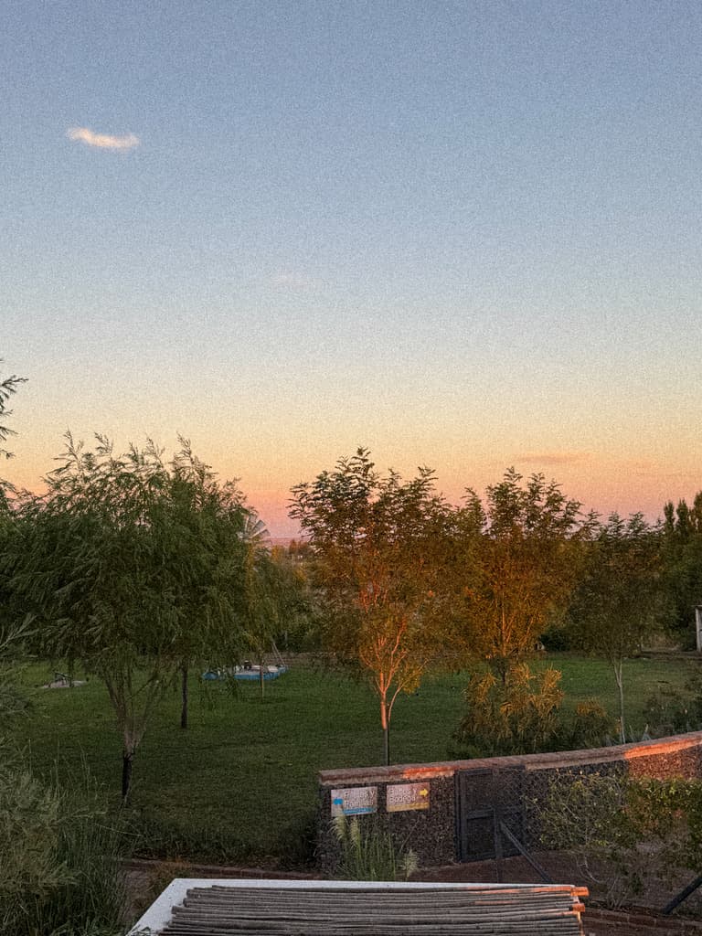 El parque al caer el sol, con dos carteles sobre el muro de piedra que señalan el camino.