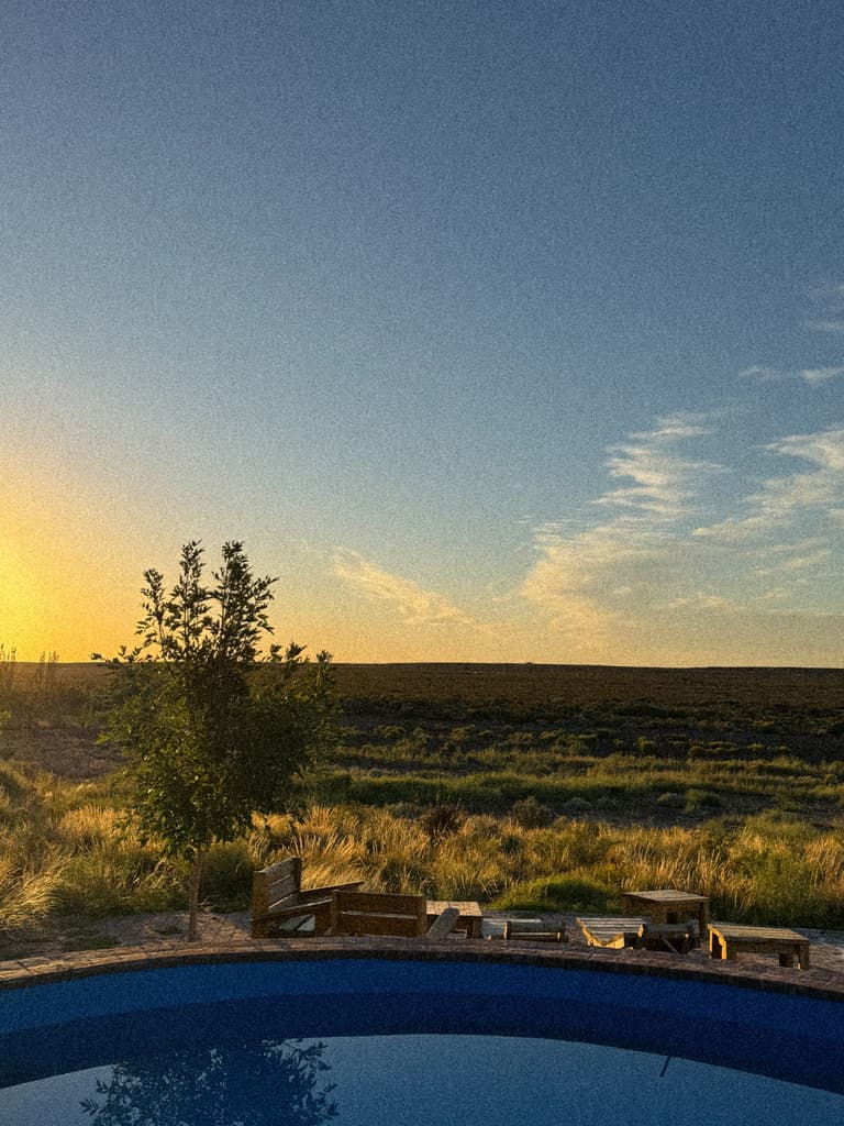 La pileta media luna al atardecer, con bancos de madera en el borde y la meseta abierta detrás.